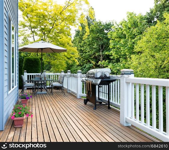 Clean outdoor cedar wooden deck and patio of home with BBQ cooker and bottled beer