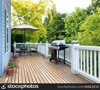 Clean outdoor cedar wooden deck and patio of home with BBQ cooker and bottled beer
