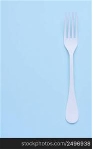 Clean white fork on trendy blue pastel background with side copy space