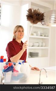 Cleaner Working In Domestic Kitchen With Feather Duster