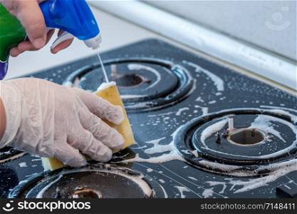 Cleaning a gas stove with kitchen utensils, household concepts, or hygiene and cleaning.. cleaning black stove