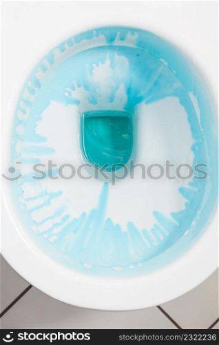 Cleaning and disinfection concept. White toilet bowl with blue detergent after flush.. White toilet bowl with blue detergent
