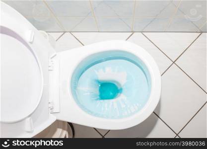 Cleaning and disinfection concept. White toilet bowl with blue detergent after flush.. White toilet bowl with blue detergent