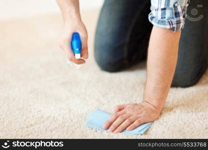 cleaning and home concept - close up of male cleaning stain on carpet with cloth