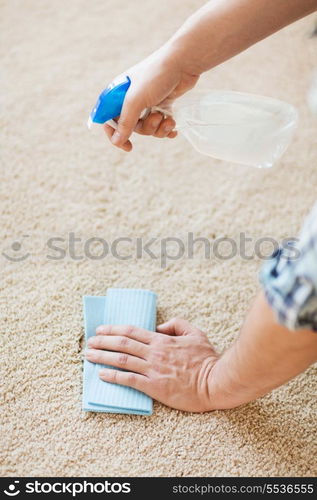 cleaning and home concept - close up of male cleaning stain on carpet with cloth