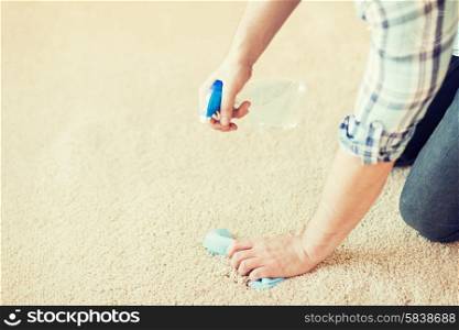 cleaning and home concept - close up of male cleaning stain on carpet with cloth