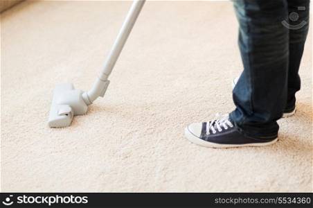 cleaning and home concept - close up of male hoovering carpet