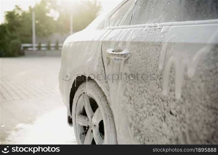 Cleaning foam on the car, hand car wash station, nobody. Car-wash industry, carwash business concept. Cleaning foam on the car