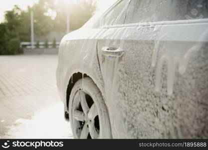 Cleaning foam on the car, hand car wash station, nobody. Car-wash industry, carwash business concept. Cleaning foam on the car