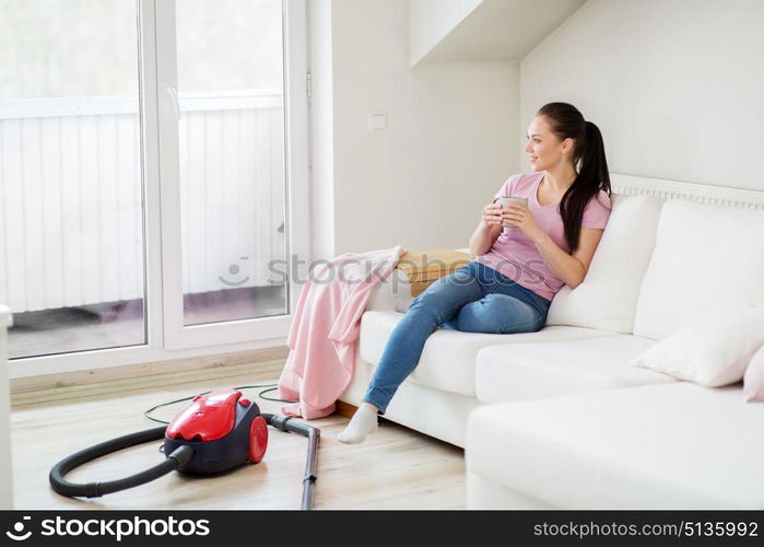 cleaning, household and people concept - happy woman or housewife with vacuum cleaner on floor drinking coffee at home. woman with vacuum cleaner drinking coffee at home. woman with vacuum cleaner drinking coffee at home