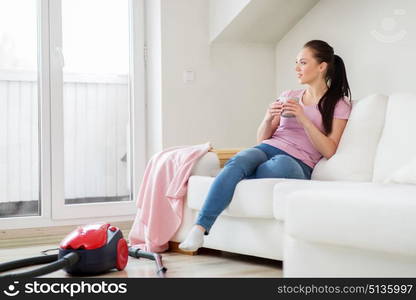 cleaning, household and people concept - happy woman or housewife with vacuum cleaner on floor drinking coffee at home. woman with vacuum cleaner drinking coffee at home. woman with vacuum cleaner drinking coffee at home