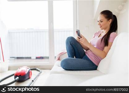 cleaning, household and technology concept - happy woman or housewife with smartphone and vacuum cleaner at home. woman with smartphone and vacuum cleaner at home. woman with smartphone and vacuum cleaner at home