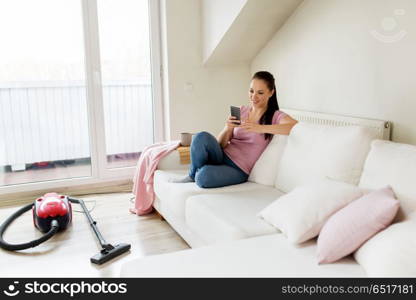 cleaning, household and technology concept - happy woman or housewife with smartphone and vacuum cleaner at home. woman with smartphone and vacuum cleaner at home. woman with smartphone and vacuum cleaner at home