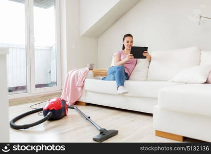 cleaning, household and technology concept - happy woman or housewife with tablet pc computer and vacuum cleaner at home. woman with tablet pc and vacuum cleaner at home. woman with tablet pc and vacuum cleaner at home