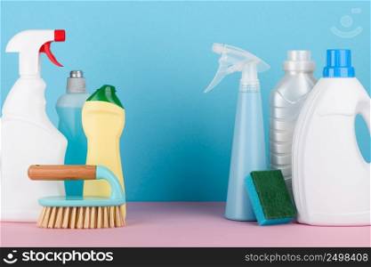 Cleaning liquids and tools set for different housework. Bathroom, kitchen, office house cleaning service equipment on pastel background with copy space in between.