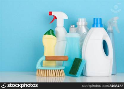 Cleaning liquids assortment and tools set for different housework on white table with copy-space.