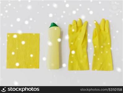 cleaning stuff, housework, housekeeping and household concept - bottle of detergent, rubber gloves and rag on white background over snow. detergent with cleaning stuff on white background
