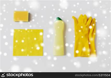 cleaning stuff, housework, housekeeping and household concept - bottle of detergent, rubber gloves with rag and sponge on white background over snow. detergent with cleaning stuff on white background