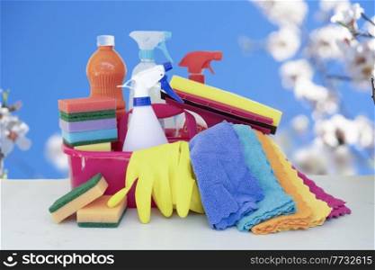 cleaning supplies tools on spring tree bloom over blue sky background, spring clean concept. cleaning supplies tools on plain background