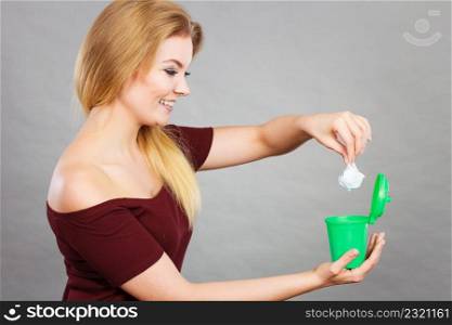 Cleaning, Woman putting paper into tiny trash can basket showing how to deal with rubbish. Woman putting paper into small trash can
