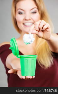 Cleaning, Woman putting paper into tiny trash can basket showing how to deal with rubbish. Woman putting paper into small trash can