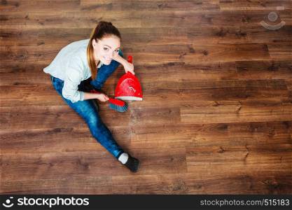 Cleanup housework concept. cleaning woman sweeping wooden floor with red small whisk broom and dustpan unusual high angle view