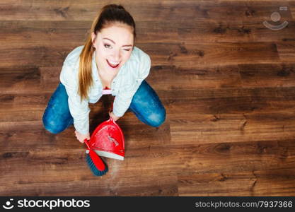 Cleanup housework concept. cleaning woman sweeping wooden floor with red small whisk broom and dustpan unusual high angle view