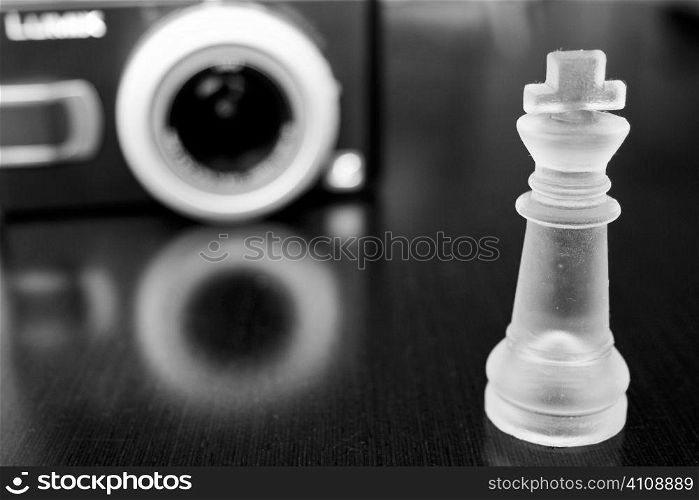 Clear chess piece and stereo speaker reflected in wooden tabletop