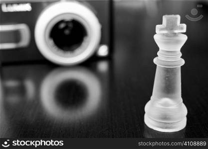 Clear chess piece and stereo speaker reflected in wooden tabletop