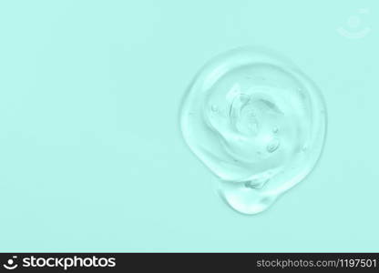 Clear liquid gel drop or smear isolated on light blue background. Copy space. Top view. Body and face care spa cosmetic concept. Serum texture.. Clear gel drop or smear isolated on light blue background. Copy space.