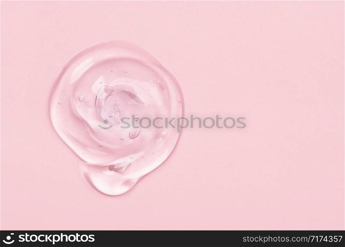 Clear liquid gel drop or smear isolated on pink background. Copy space. Top view. Body and face care spa cosmetic concept. Serum texture.. Clear gel drop or smear isolated on pink background.