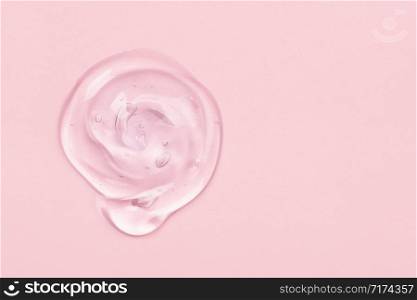 Clear liquid gel drop or smear isolated on pink background. Copy space. Top view. Body and face care spa cosmetic concept. Serum texture.. Clear gel drop or smear isolated on pink background.
