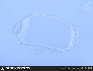 Clear liquid gel smear isolated on blue background. Top view. Body and face care spa cosmetic concept, Serum texture.. Clear gel smear isolated on blue background. Top view.