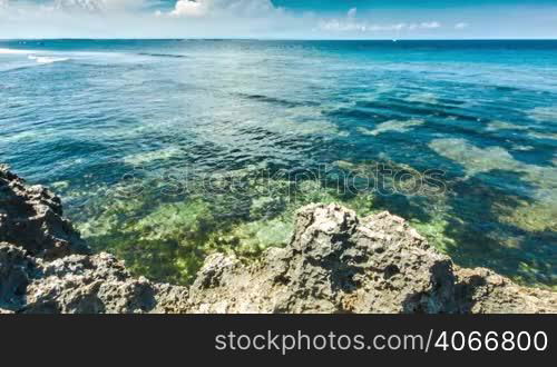 Clear ocean waves with sharp rocks shore