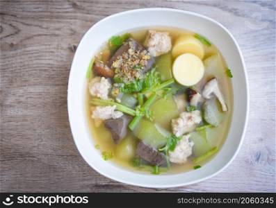 Clear soup blood pork thai healthy food asian on dark background, Tofu Soup bolw with winter melon vegetable eggs tofu slice meat ball and minced pork with celery, top view