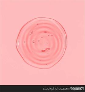Clear transparent round spiral liquid pink gel drop or smear isolated on pink background. Top view. Virus protection or cosmetics concept. Serum texture.. Clear transparent round spiral liquid pink gel drop or smear isolated on pink background. Top view. Virus protection or cosmetics concept. Serum texture