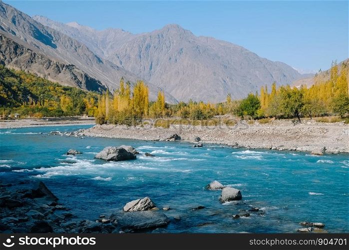 Clear turquoise blue water river flowing along Hindu Kush mountain range in Ghizer valley. Autumn scenery in Gilgit Baltistan, Pakistan.