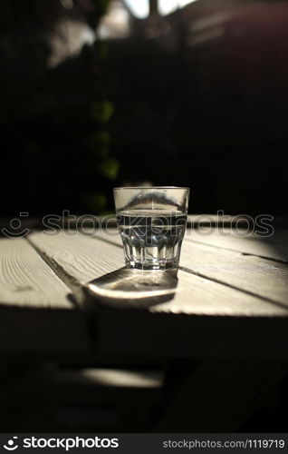 Clear water in a clear glass against. Healthy food and environmentally friendly natural water. a glass of water on a wooden table. Clear water in a clear glass against. Healthy food and environmentally friendly natural water. a glass of water on a wooden table.