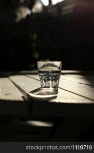 Clear water in a clear glass against. Healthy food and environmentally friendly natural water. a glass of water on a wooden table. Clear water in a clear glass against. Healthy food and environmentally friendly natural water. a glass of water on a wooden table.