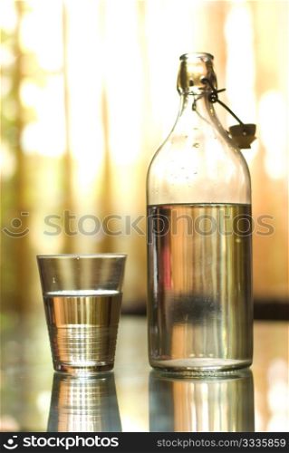 Clear water in glass bottle and cup on the table
