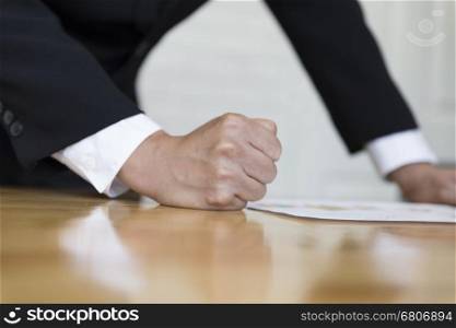 clenched fist of businessman on office desk - angry and furious business concept
