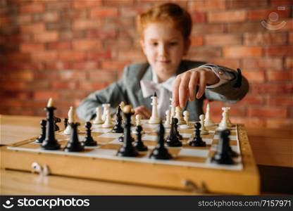 Clever schoolgirl, chess player at the table. Young girl at the chessboard, female kid plays logic game. Clever schoolgirl, chess player at the table