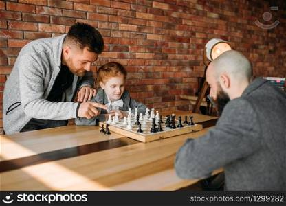 Clever schoolgirl playing chess with man. Young girl at the chessboard, female kid plays logic game