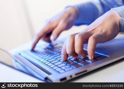 Click! Hands of a man on a keyboard with blue backlighting.