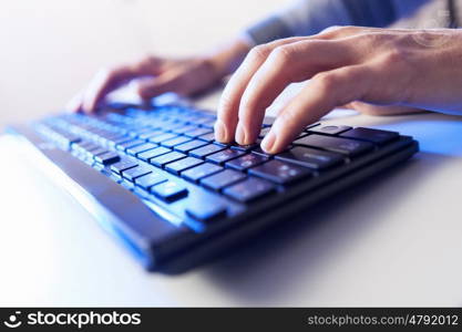 Click! Hands of a man on a keyboard with blue backlighting.