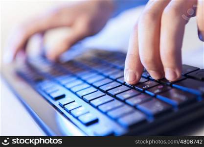 Click! Hands of a man on a keyboard with blue backlighting.