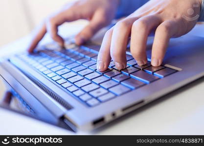 Click! Hands of a man on a keyboard with blue backlighting.