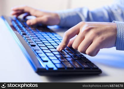 Click! Hands of a man on a keyboard with blue backlighting.