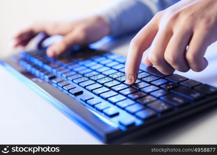 Click! Hands of a man on a keyboard with blue backlighting.