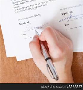 client signs an agreement by silver pen on table